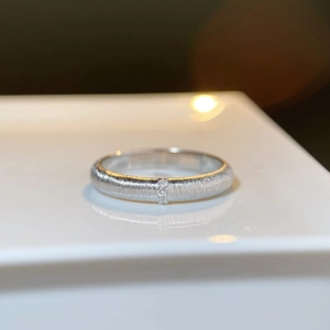 Detail of brushed 925 sterling silver ring with three micro-set diamonds on white stand