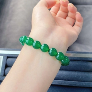 Détail d'un bracelet en calcédoine verte au poignet avec un éclat rappelant le jade