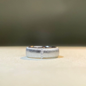 Macro detail of wide brushed silver ring featuring a vertical row of white diamonds