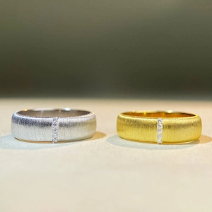 Detailed macro view of silver and gold brushed rings with vertical five-diamond settings