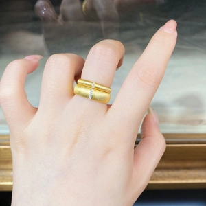 Detailed close-up of a wide brushed 18K gold ring with vertical small white stones