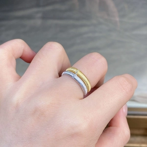 Detail of brushed gold and silver rings with small diamonds on hand