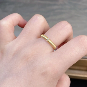 Detailed view of matte brushed 18K gold ring featuring three inlaid round zircons