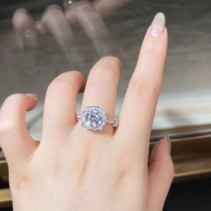 Macro detail of round moissanite ring with halo setting and pavé band on finger