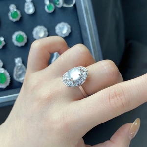 Detail shot of a silver ring with an oval white gemstone and halo crystals on hand