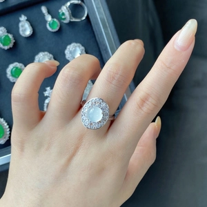 Macro detail of a vintage white chalcedony ring with a sparkling halo on a hand