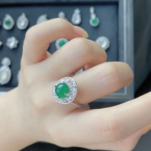 Close-up of imperial green chalcedony oval ring with halo diamond setting on hand