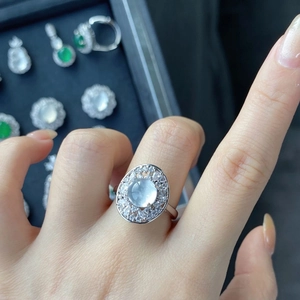 Macro detail of a silver ring with white oval gemstone and surrounding crystal pave setting