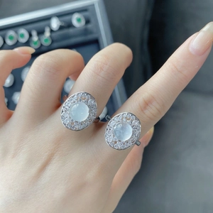 Close-up of adjustable silver rings with oval translucent gemstones and halo diamonds