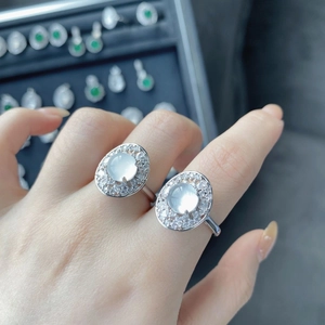 Macro detail of oval white chalcedony rings with sparkling halo setting on hand