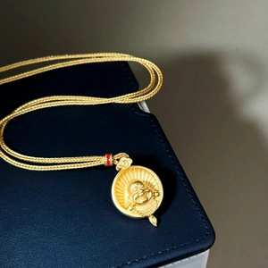 Close-up of 18K gold-plated Buddha pendant on an intricate braided chain necklace