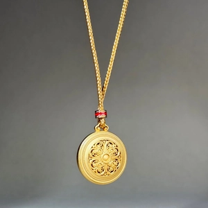 Classic round gold pendant necklace with intricate filigree and red accent detail