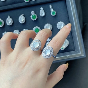 Close-up of silver rings with oval translucent chalcedony and diamond halo on female hand