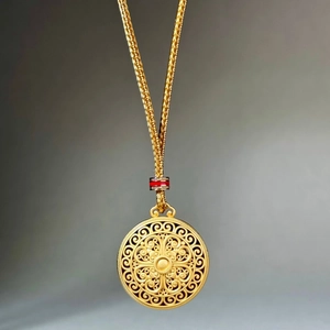 Detail of vintage gold filigree pendant necklace with red beads on long braided chain