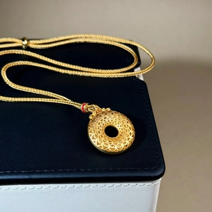 Detailansicht der goldenen Mandala-Halskette auf einer schwarzen Schmuckschatulle