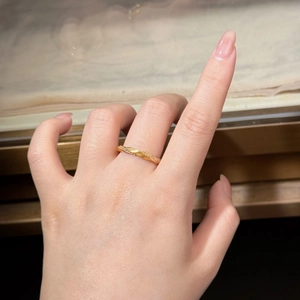 Close-up of golden Mobius twist ring with small diamonds on female index finger
