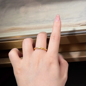 Detail of twisted rope gold ring with diamond accents worn on a finger in close-up