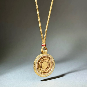 Close-up of golden compass pendant necklace featuring intricate cutout patterns and pavé crystals