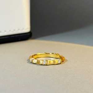 Macro detail of gold bamboo joint ring with brushed texture and tiny inlaid diamonds