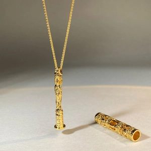 Collier avec pendentif cylindre en filigrane doré, gravures en relief et chaîne torsadée