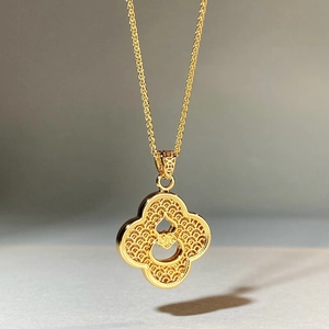 Gold-plated clover pendant necklace with intricate filigree texture and woven chain