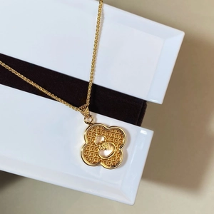 Detailed macro view of a gold-plated necklace with a clover gourd pendant inside a box