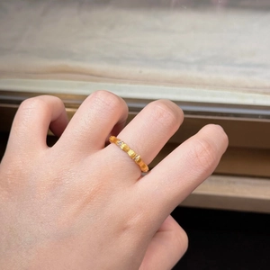 Close-up of brushed gold bamboo ring with diamond accents on model's hand