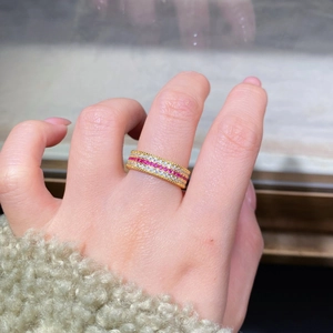 Gros plan d'une bague en argent doré ornée de pierres roses et blanches au doigt