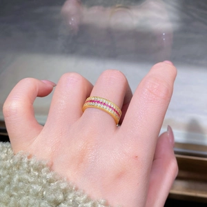 Détail d'une bague de luxe dorée avec trois rangées de zircons rouges et blancs fins
