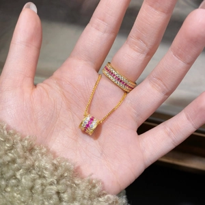 Détail de parure de bijoux dorés avec pierres de zircon rouges et blanches sur un modèle