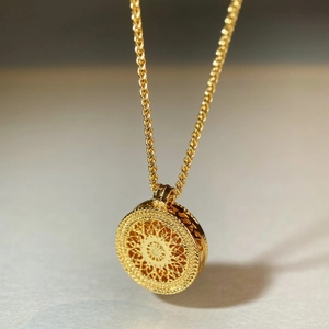 Macro shot of gold compass pendant featuring hollow patterns and side heart details