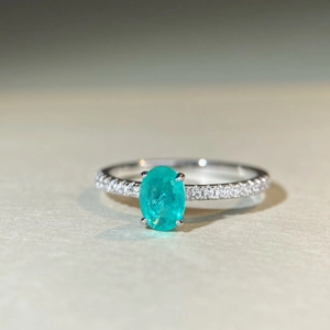Macro shot of oval cut Paraiba blue stone in a four-prong silver ring setting
