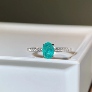 Macro shot of oval Paraiba blue-green gemstone ring with pavé diamond band