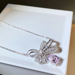 Macro detail of silver bow pendant with pink pear-cut zircon and shimmering micro-pave