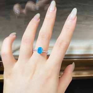 Gros plan sur bague en argent S925 avec pierre bleue ovale et détails diamantés