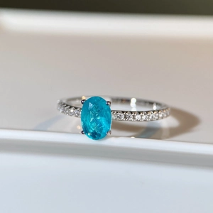 Macro shot of oval-cut paraiba blue gemstone ring with micro-pave silver band