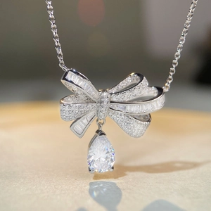 Macro detail of silver bow pendant with teardrop stone and shimmering micro-pave diamonds