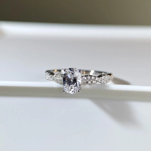 Macro view of 1 carat oval cut moissanite ring with twisted pavé-set silver band