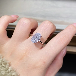 Close-up of a large oval cut sparkling diamond ring with a four-prong setting on a hand