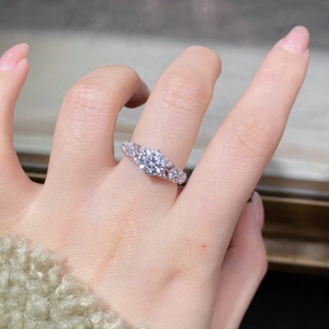 Gros plan d'une bague moissanite 1ct avec anneau argenté ajouré et pierres sur doigt