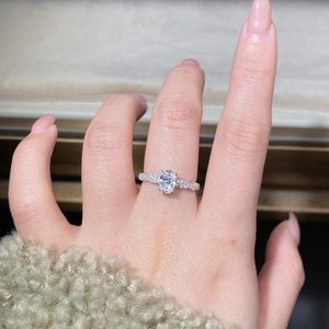 Close-up of 1ct oval moissanite ring with twisted pavé band on model's hand