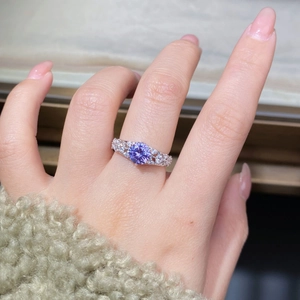 Gros plan d'une bague en argent avec moissanite violette ronde et détails pavés