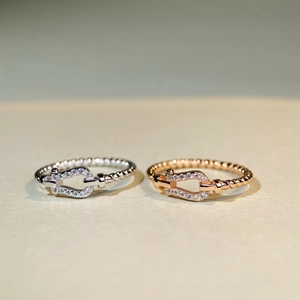 Macro detail of silver and rose gold horseshoe rings with cubic zirconia and beaded band