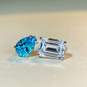 Detalle de anillo Toi et Moi con gema azul pera y piedra clara de talla esmeralda