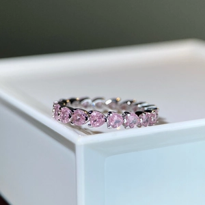 Macro detail of 925 silver ring featuring a full circle of pink heart-shaped gemstones