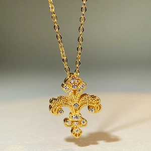 Dettaglio macro del ciondolo a giglio dorato con design traforato e accenti in zircone bianco