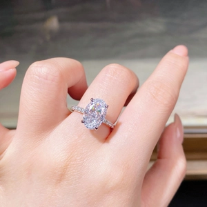 Close-up of oval cut high-carbon yellow diamond ring worn on finger with pavé band