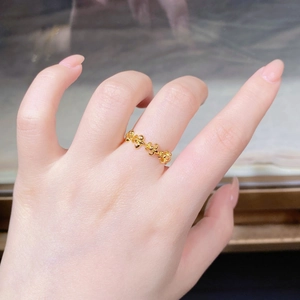 Detail view of gold floral eternity ring featuring intricate 3D petal design on finger