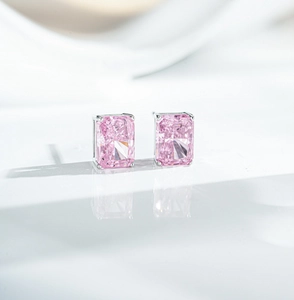 Macro shot of pink radiant cut earrings with four-prong silver settings on white reflective surface