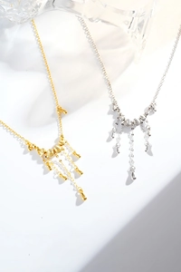 Détail de colliers à glands argent et or avec perles brossées et pendentifs goutte d'eau